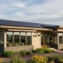 Modern sustainable house with solar panels and energy-efficient windows surrounded by native landscaping