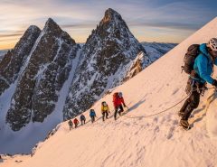 Mountaineers ascending a snow-covered peak in California's Sierra Nevada mountain range with climbing gear