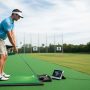 Golfer using a portable launch monitor on a driving range to measure ball speed and launch angle