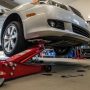 Hydraulic floor jack lifting a car in a garage