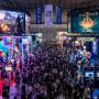 A packed exhibition hall at Tokyo Game Show 2026 at Makuhari Messe in Chiba, Japan, with colorful gaming booths, giant screens displaying game trailers, and thousands of visitors