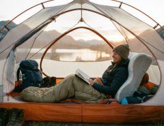 Compact memory foam camping pillow beside a hiking backpack on a wooden table.