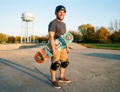 Beginner adult holding a skateboard at an Illinois skatepark