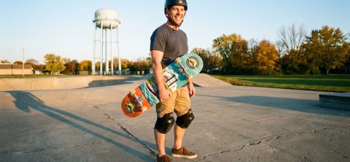 Beginner adult holding a skateboard at an Illinois skatepark