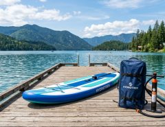 Fully inflated paddle board with pump and storage bag on a dock.