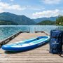 Fully inflated paddle board with pump and storage bag on a dock.