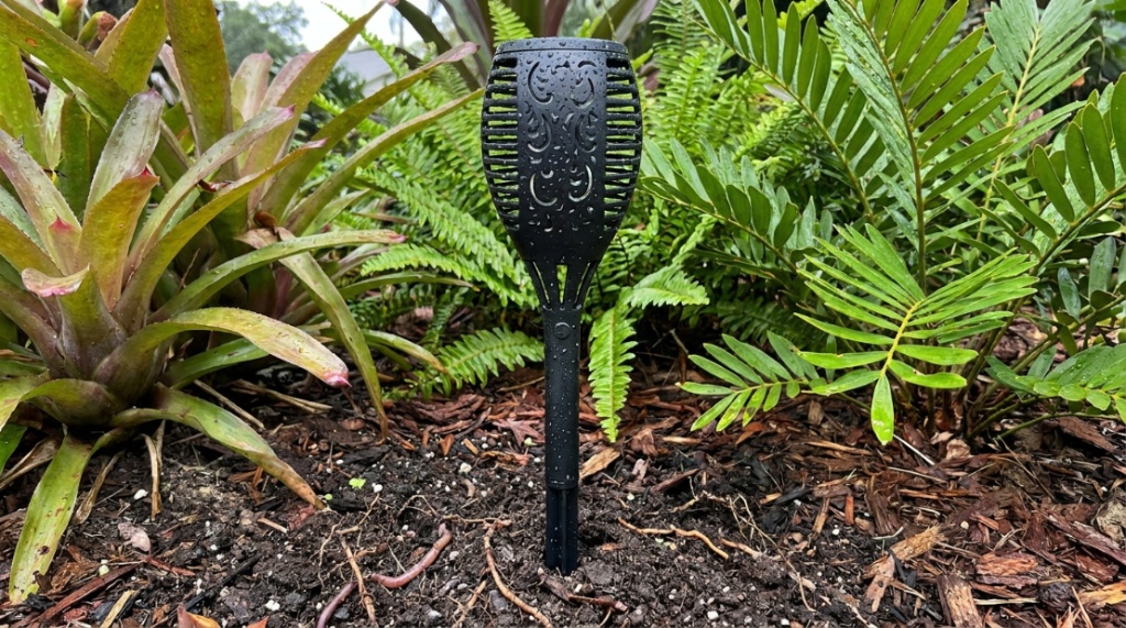 Durable waterproof solar garden torch planted securely in tropical landscaping.